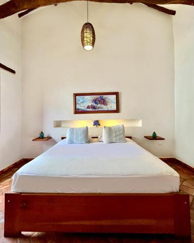 a bedroom with a large bed with white sheets at Misia Custodia Hotel Boutique in Barichara