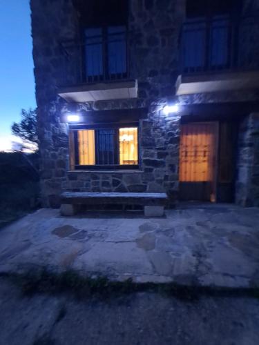 a stone house with lights on the windows at night at La Fragua I y II in Rebollar