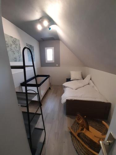 a attic room with a bunk bed and a ladder at Le bien être aux forges in Céaux