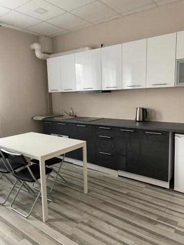 a kitchen with white cabinets and a table in it at Brēžas apartamenti in Valmiera