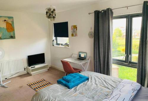 a bedroom with a bed and a desk and a television at Marigold Private double room in London