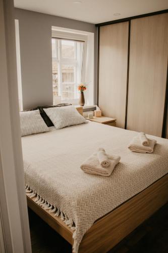 a bedroom with two towels on a bed with a window at Vītola apartamenti in Kuldīga