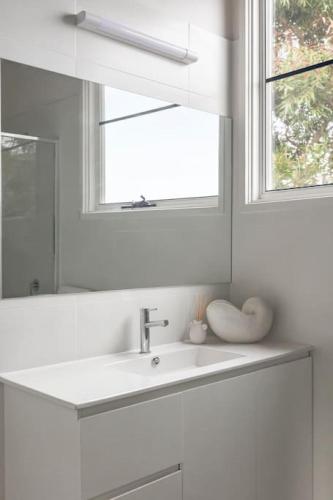 a white bathroom with a sink and a mirror at Surfcoast Soul - Stylish Dog Friendly Retreat - Torquay in Torquay