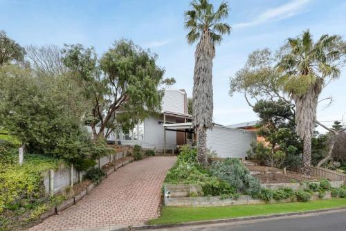 a house with palm trees and a driveway at Surfcoast Soul - Stylish Dog Friendly Retreat - Torquay in Torquay