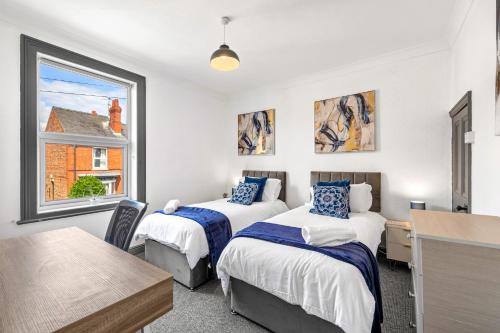 a bedroom with two beds and a desk and a window at Lincoln House Sleeps 6-8! Close to City and University! in Lincolnshire