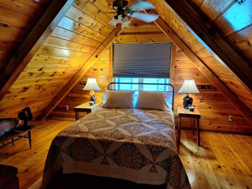 a bedroom with a bed in a wooden attic at Neshannock Creekside Log Cabin in Volant