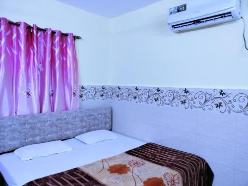 a bedroom with a bed with pink curtains at Beach Xaviers Guest House Colva in Colva