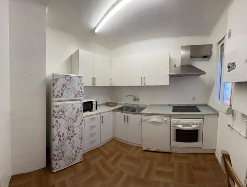 a kitchen with white cabinets and a refrigerator at Cal Boix Apartamento in Tremp
