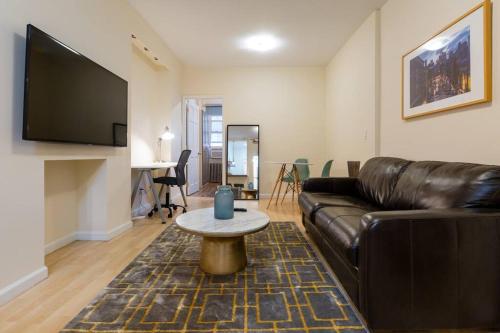 a living room with a leather couch and a table at Comfortable Apartment with Workstation in New York