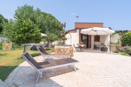a patio with two chairs and a table and an umbrella at Siracusa mare in Arenella