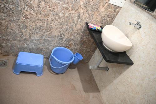 a bathroom with a sink and a blue trash can at HOTEL PRITAM PARK in Jālgaon