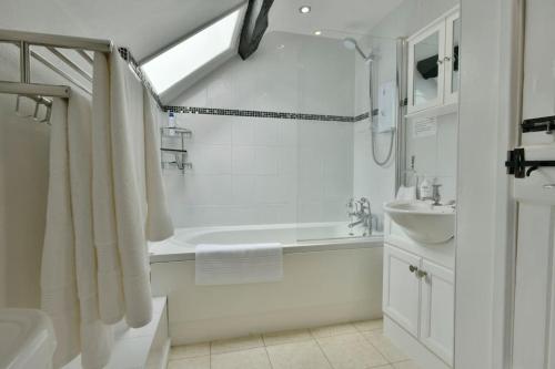 a white bathroom with a tub and a sink at Tranquil Apartment at Ashton in Sidmouth