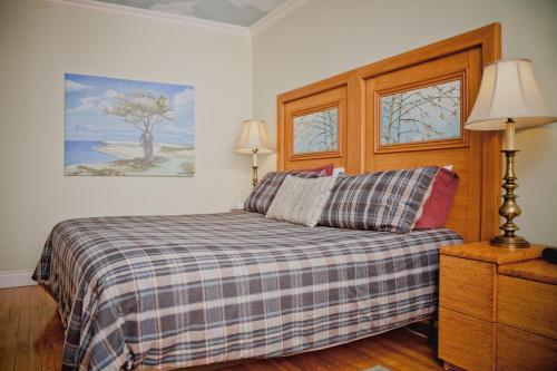 a bedroom with a bed with a plaid blanket and two windows at Maison Des Jardins B & B in Montréal