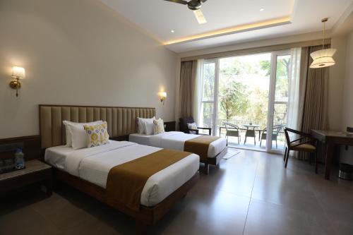 a hotel room with two beds and a balcony at Golden Fields Resort in Mulshi
