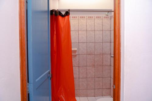 a bathroom with a shower with an orange shower curtain at Yaki Hostel in Lima