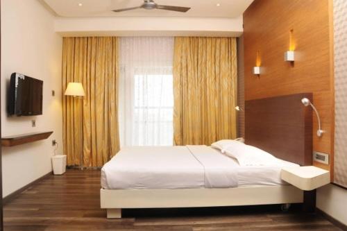 a bedroom with a large bed and a television at Hotel Indraprastha in Palakkad
