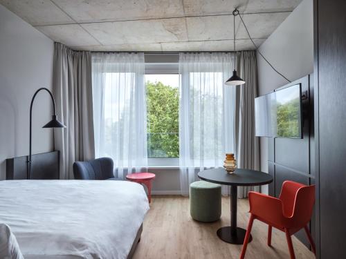 une chambre d'hôtel avec un lit, une table et des chaises dans l'établissement STAYERY Bremen, à Brême