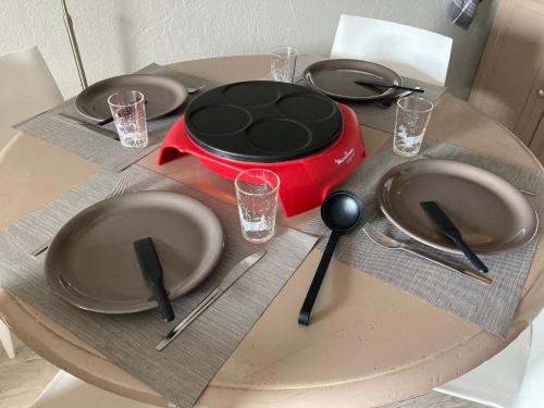 a table with plates and utensils on a table at Au pied des pistes Côte 2000 - Le Balcon de Villard de Lans in Villard-de-Lans
