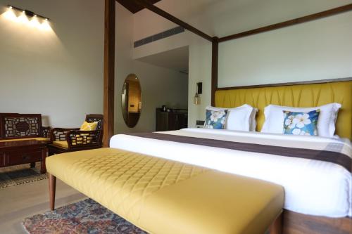 a bedroom with a large bed with a bench in it at Golden Fields Resort in Mulshi