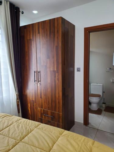 a large wooden cabinet in a bedroom with a toilet at Home away from home #1 in Accra