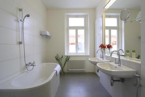 a white bathroom with two sinks and a bath tub at James Hotel & Apartments in Prague