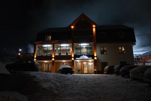 a building with lights on in the snow at night at Alpejski Zieleniec in Duszniki Zdrój