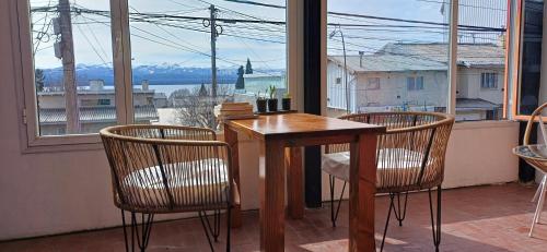 una mesa de madera y 2 sillas frente a una ventana en Nina Hostel, en San Carlos de Bariloche