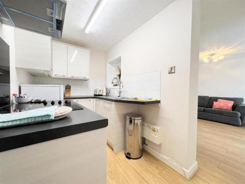 a kitchen with white cabinets and a black counter top at Newquay Fistral Beach View in Newquay