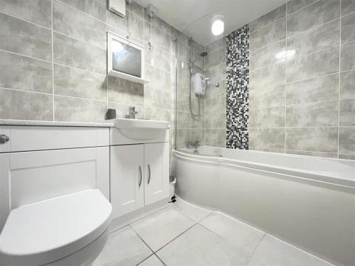 a bathroom with a toilet and a tub and a sink at Newquay Fistral Beach View in Newquay