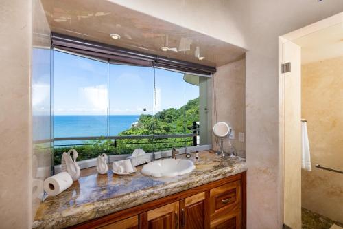 Un baño con lavabo y una gran ventana. en Boca de Tomatlán Ocean Frontage Boutique Hotel, en Puerto Vallarta