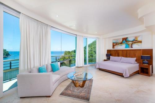 um quarto com uma cama, um sofá e uma mesa em Boca de Tomatlán Ocean Frontage Boutique Hotel em Puerto Vallarta