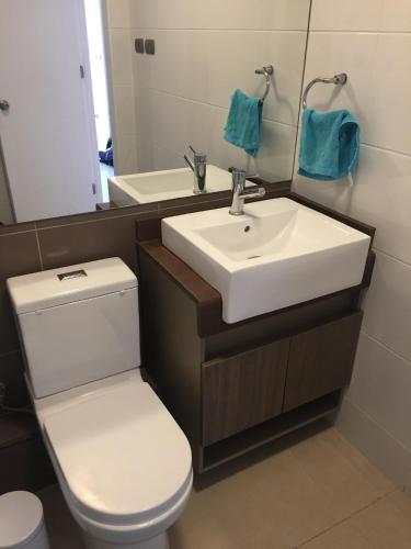 a bathroom with a sink and a toilet and a mirror at Acogedor departamento a pasos de la playa in Coquimbo