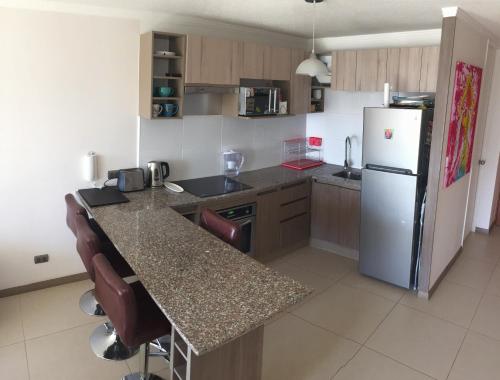 a kitchen with a refrigerator and a counter top at Acogedor departamento a pasos de la playa in Coquimbo