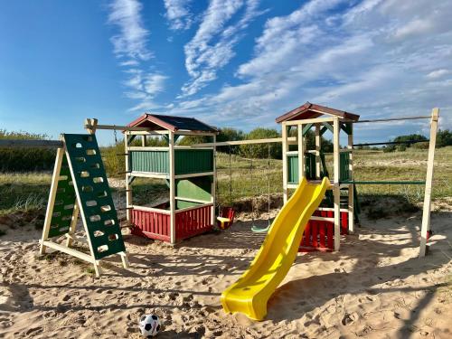 un parque infantil con equipo de juegos en la arena en Eco-House Ainaži, en Ainaži