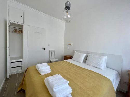 a white bedroom with a large bed with towels on it at Apartamento muito central - 300 metros da Praia in Costa da Caparica