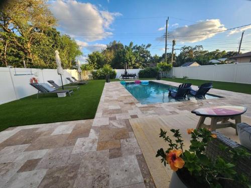 a backyard with a pool with chairs and a table at Saltwater pool, FREE beach passes & GREAT location! in Boynton Beach