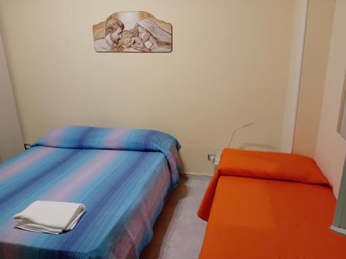 1 dormitorio con 2 camas y silla naranja en Casa relax, en Vibo Valentia Marina