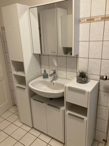 a white bathroom with a sink and a mirror at Zimmervermietung Familie Hund in Leinefelde