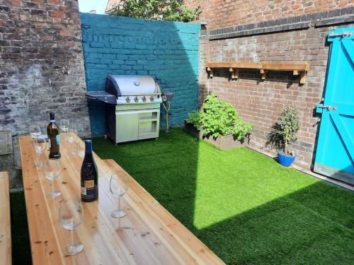 a backyard with a grill and a table with wine glasses at Anfield Haven in Liverpool