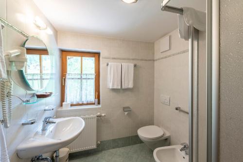 a white bathroom with a sink and a toilet at Hotel Walter in San Candido