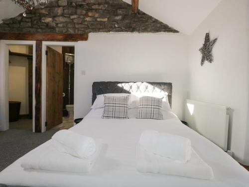 - une chambre avec un grand lit blanc et des oreillers dans l'établissement Cobble Cottage, à Kendal