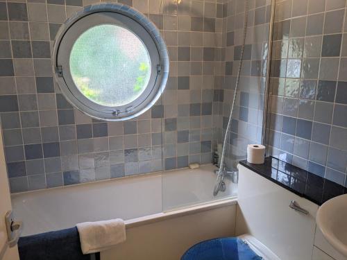 a bathroom with a tub and a round window at Rotherhithe apartment near park and river in London