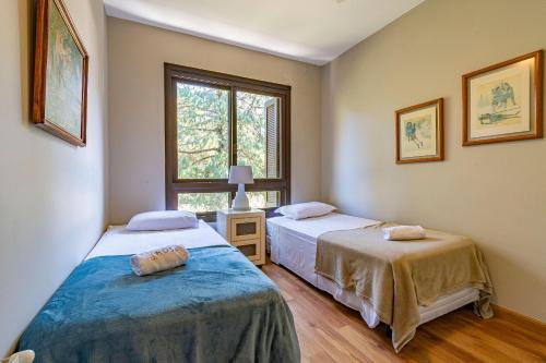 a bedroom with two beds and a window at Rosa Edifício KnorrVille in Gramado