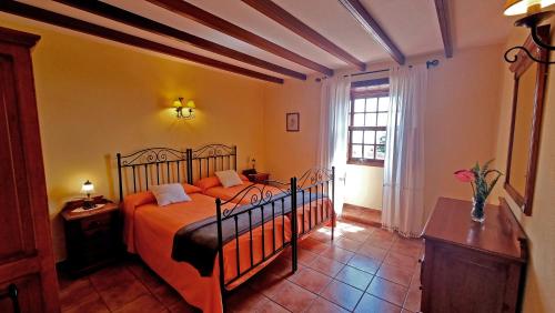 ein Schlafzimmer mit einem Bett mit orangefarbener Bettwäsche und einem Fenster in der Unterkunft Los Nacientes: Cordero in Los Sauces