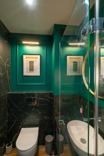 a bathroom with green walls and a toilet and a sink at Noche Apartamenty Premium in Biała Podlaska