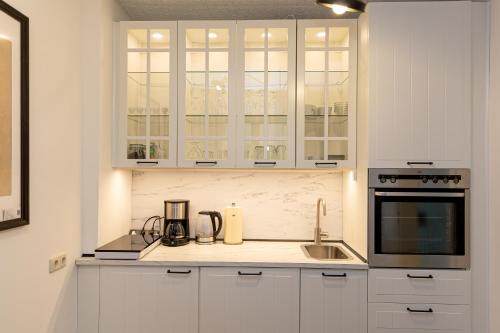 uma cozinha branca com armários brancos e um lavatório em NickHaus em Cochem