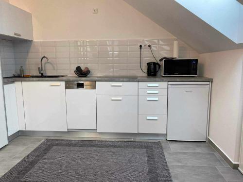 a kitchen with white cabinets and a microwave at Csipke Residence 3 in Hajdúszoboszló