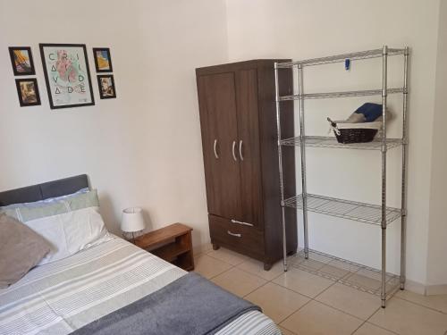 サンパウロにあるSuíte com banheiro super espaçosaのベッドルーム1室(ベッド1台付)、木製キャビネットが備わります。