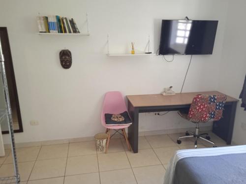 サンパウロにあるSuíte com banheiro super espaçosaのベッドルーム(デスク、ピンクの椅子、テーブル付)