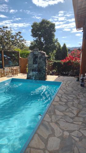 a swimming pool with a water fountain in a yard at Pousada Mangaba da Serra in Serra do Cipo